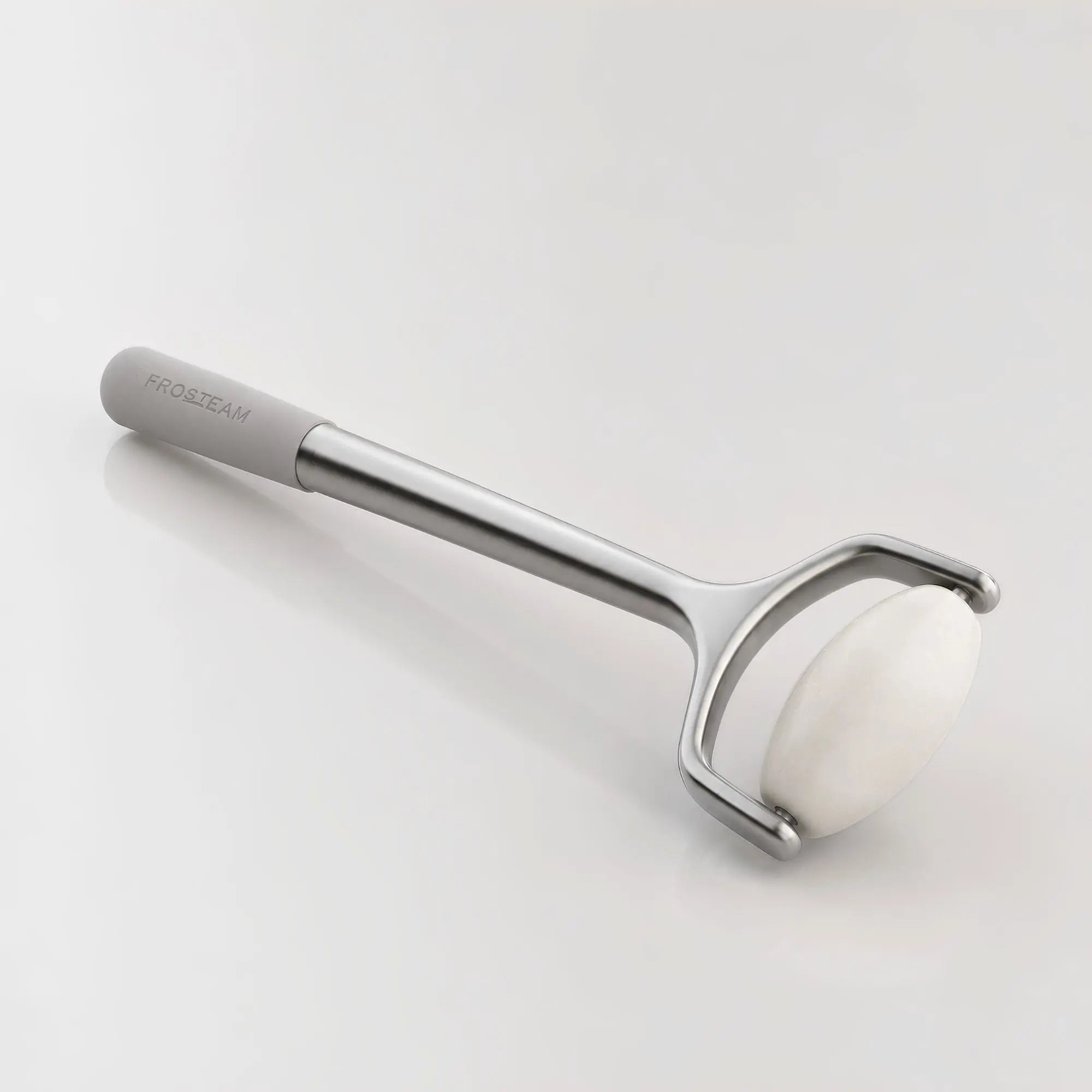 Frosteam facial roller with natural white jade stone and stainless steel handle on a minimalist luxury studio background.