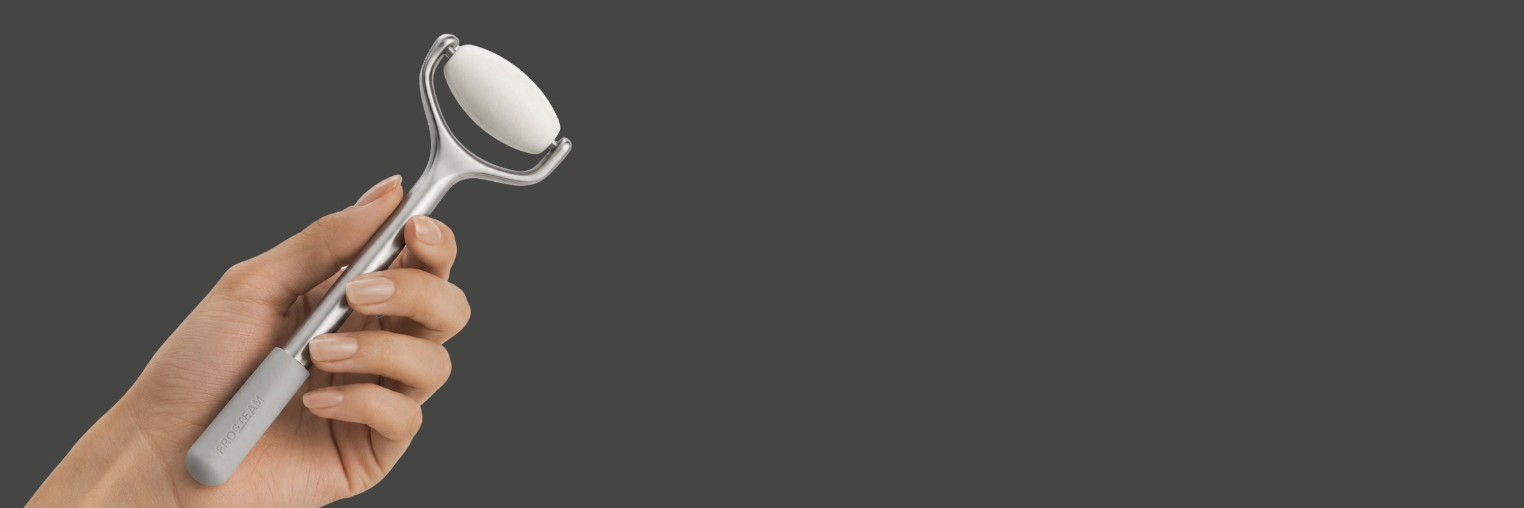 Hand holding the Frosteam Face Roller with stainless steel handle and cooling stone head