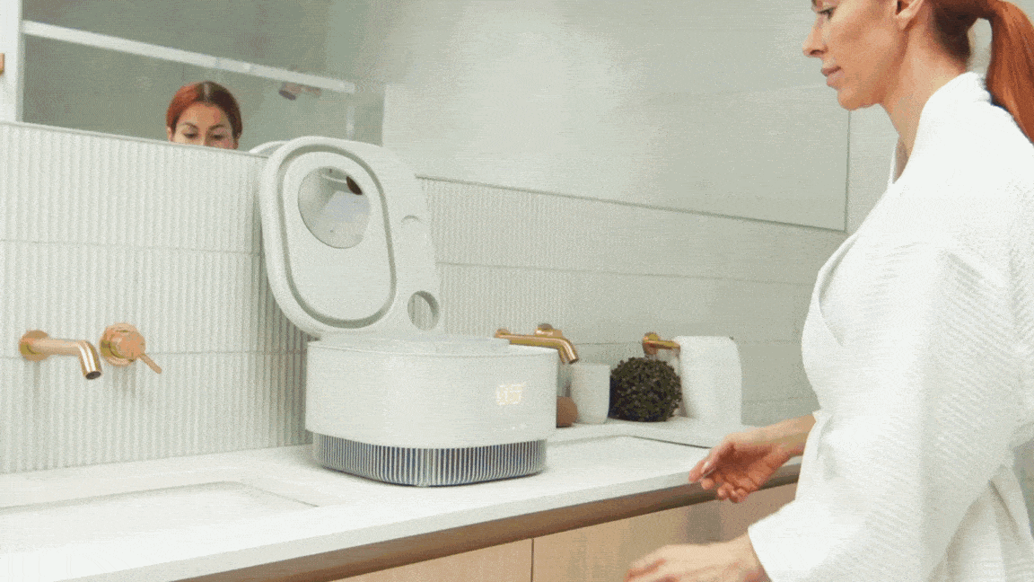 Woman using Frosteam device for a nano-ionic steam facial treatment