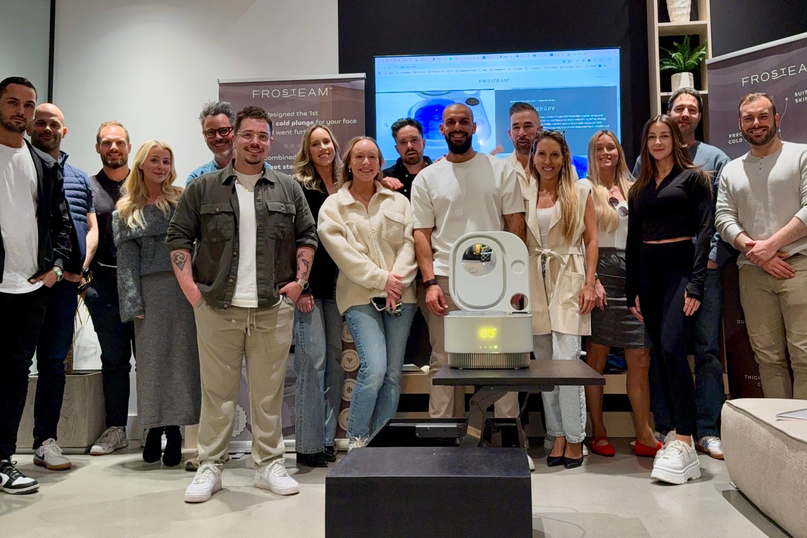 The Frosteam team gathered around the device during a product presentation, highlighting collaboration, innovation, and the development of the Frosteam skincare technology