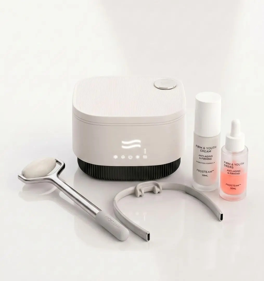 Frosteam 3-in-1 hot and cold facial device bundle with stainless steel facial roller, gua sha tool, Firm and Youth firming cream, and Aqua Drops cold therapy serum on white studio background