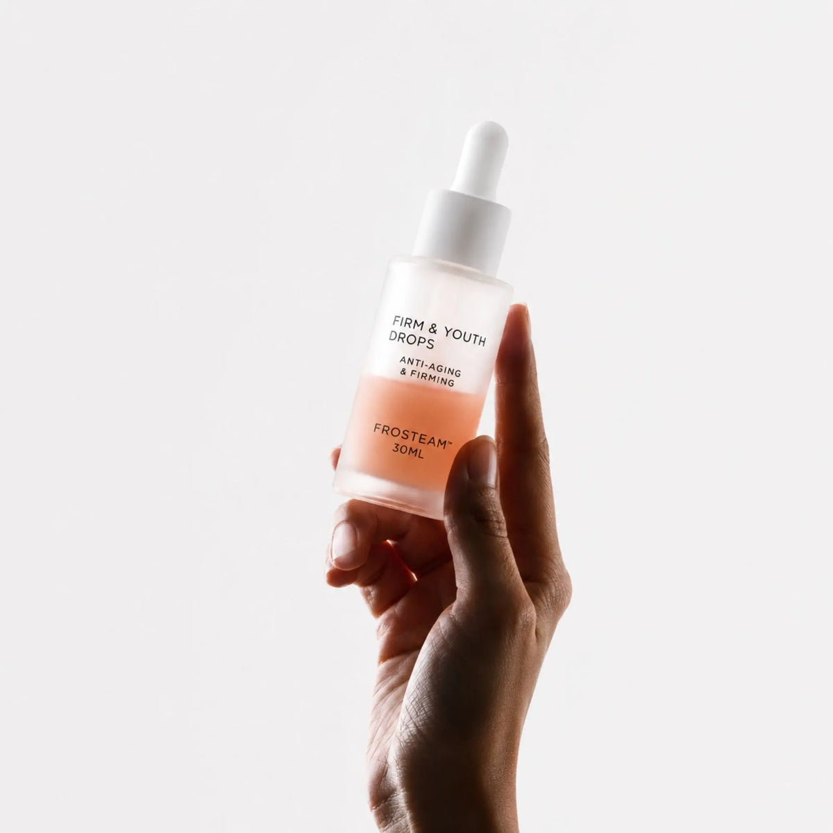 Hand holding Frosteam Aqua Drops Cold Therapy Serum bottle