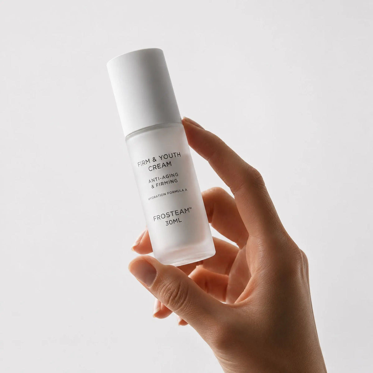 Hand holding Frosteam Firm and Youth Anti-Aging and Firming Cream bottle
