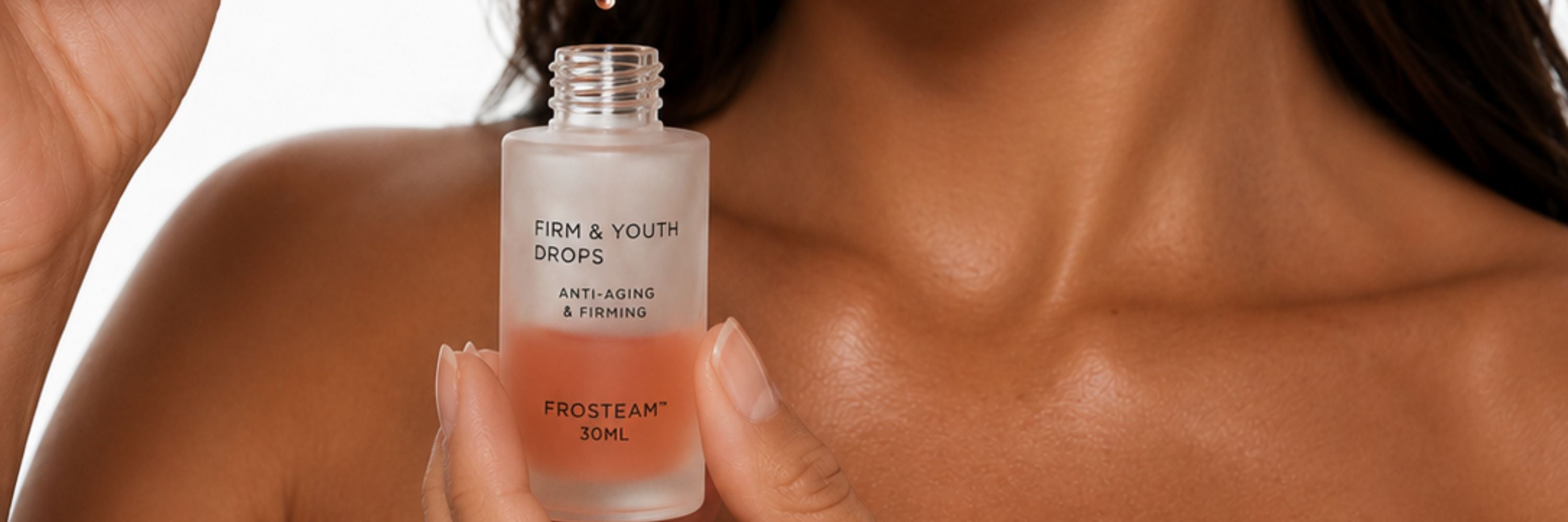 Woman holding the Frosteam Aqua Drops serum bottle near her collarbone