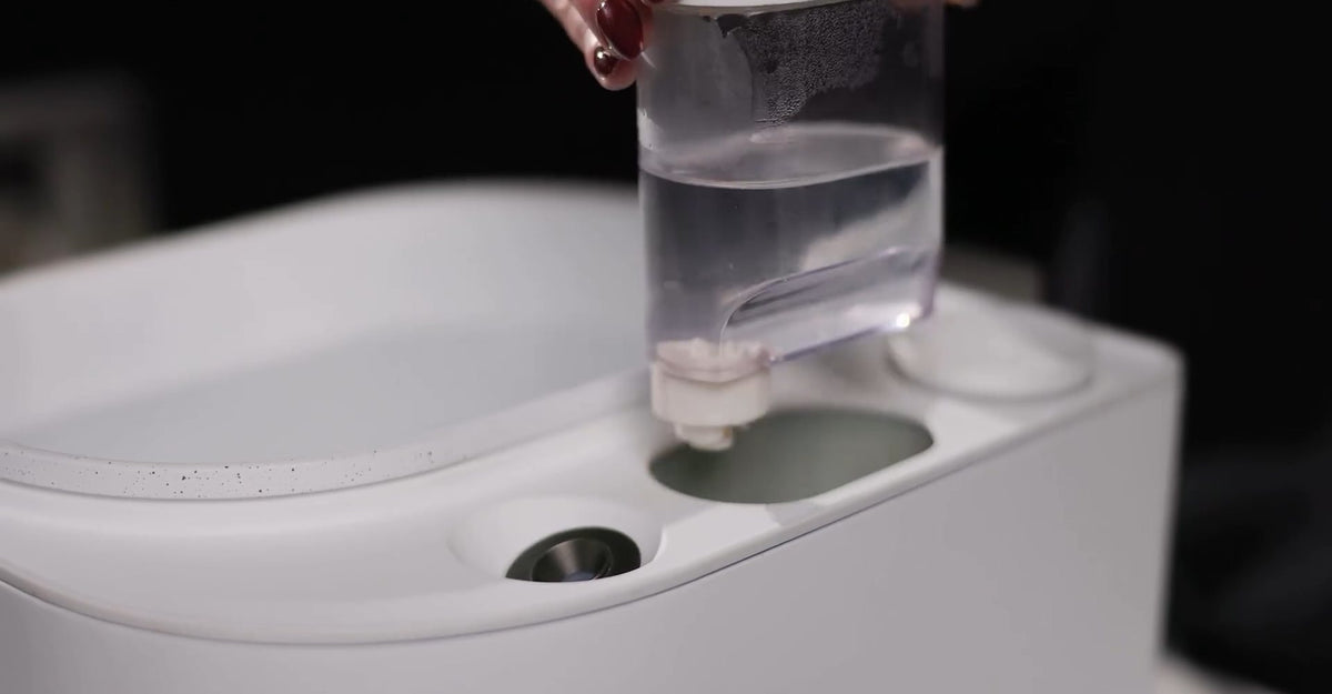 Hand placing the filled water tank into Frosteam Harmony to feed the nano-ionic steam outlet