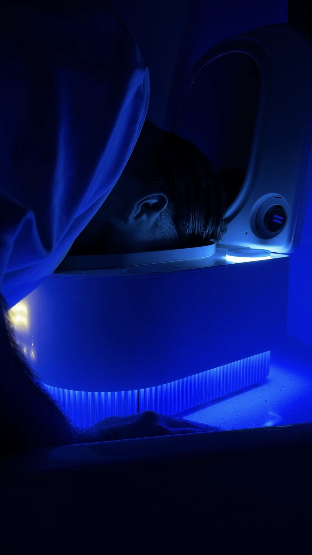 Man doing a Frosteam Harmony steam ritual under a towel, device glowing blue